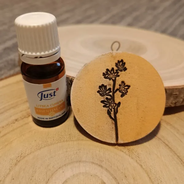 Kulatý keramický aroma přívěsek s otiskem rozkvetlé větvičky vedle lahvičky olejíčku